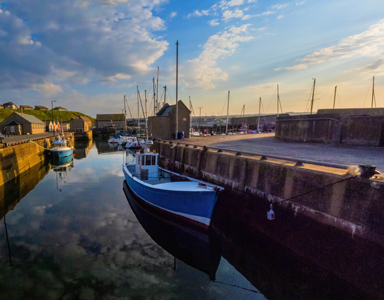a wall art piece featuring a serene harbour just before sunset, evoking calmness with gold sunlight and a warm blue gold tint sky reflecting in pure still peaceful waters, a very welcome sight after the storms of late...